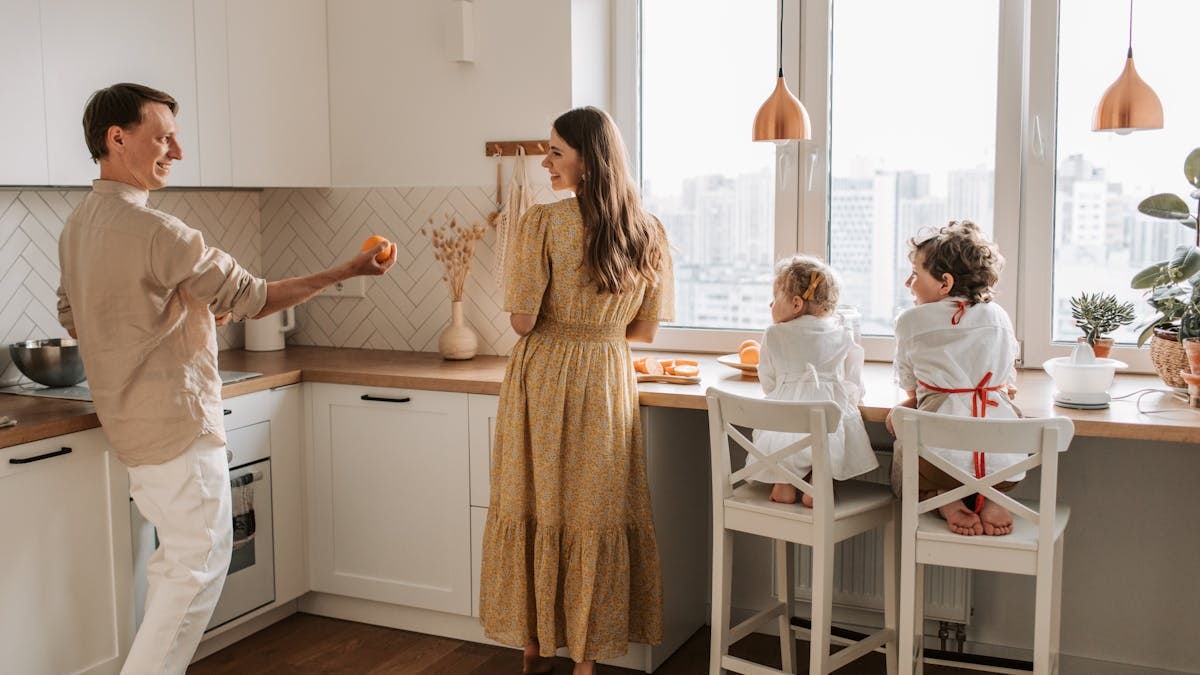 A family having fun preparing breakfast in a cozy kitchen with a city view.